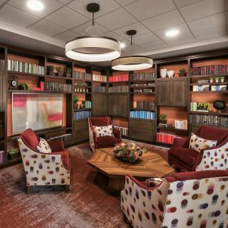 A cozy library with armchairs and wooden bookshelves filled with books.