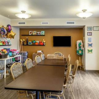 A decorated meeting room with a long table, surrounded by chairs, and colorful balloons.