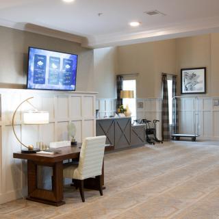 A modern office interior featuring a workstation with a desk, lamp, and wall-mounted TV.