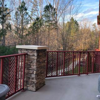 A peaceful balcony overlooking a wooded area with clear skies.