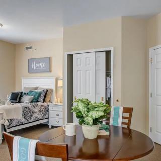 A cozy bedroom with a neatly made bed, small dining table, and stylish decor.