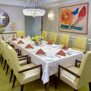 A formal dining room with an elegantly set table, featuring a chandelier and colorful artwork.