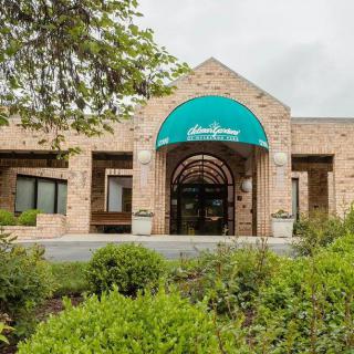A brick building entrance with a green awning and surrounding greenery.