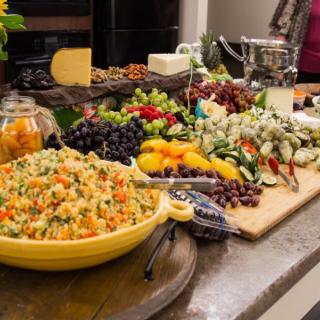 A vibrant buffet spread featuring couscous salad, fresh fruit, cheese, and vegetables.