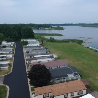 Aerial view of houses by a lake with a road and surrounding greenery.