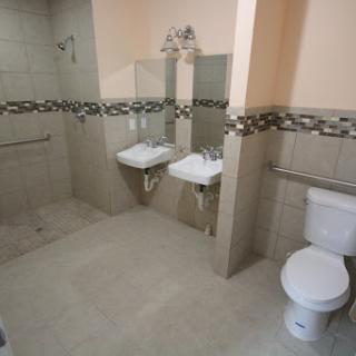 A modern bathroom featuring two sinks, a toilet, and tiled walls.