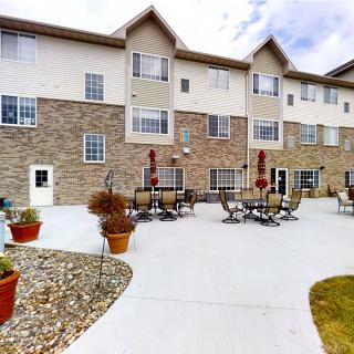 A residential building with an outdoor patio area featuring tables and chairs.