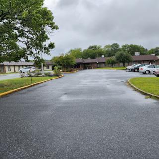 A view of a vacant parking lot surrounded by buildings under a cloudy sky.