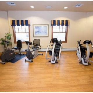 A small gym with stationary bikes and wooden flooring.