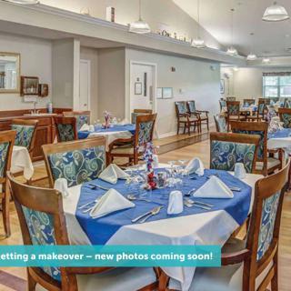 A well-appointed dining room with neatly set tables and blue tablecloths, ready for guests.