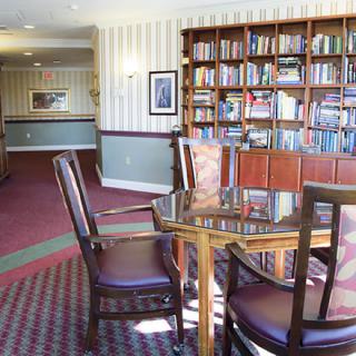 A cozy library reading area with a bookshelf and table with chairs.