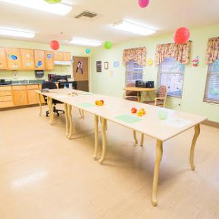 A brightly lit kitchen area with a long dining table set up for activities, adorned with colorful decorations.
