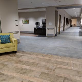 A spacious and modern lobby area featuring a green couch, with a well-lit hallway leading to various rooms.