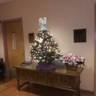 A beautifully decorated Christmas tree with lights, standing on a table in an indoor setting.