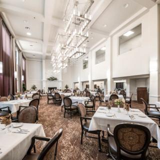 An elegant dining room with beautifully set tables and large chandeliers.