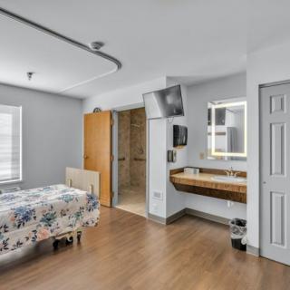 A modern hospital room featuring a bed, wood flooring, and an accessible bathroom.