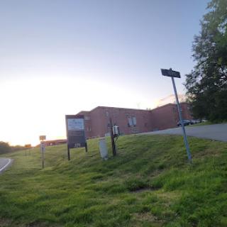 A tranquil scene of a building at sunset, surrounded by lush grass and directional signs.