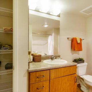 A clean and well-organized bathroom with a wooden cabinet, sink, mirror, and neatly arranged towels.