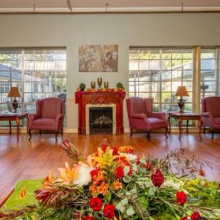 A cozy living room with a fireplace, elegant chairs, and a floral centerpiece.