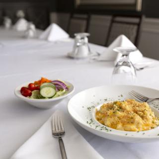 A beautifully set dining table featuring a delicious plate of pasta and a fresh salad.