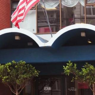 An entrance to a building with an American flag and blue awning.