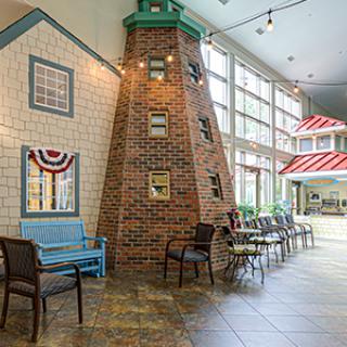 An indoor setting with a nautical theme, featuring a lighthouse structure and seating area next to large windows.