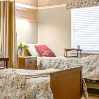 A neatly arranged hospital room with two beds, featuring soft lighting and cozy decor.