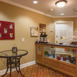A cozy reception area featuring a coffee station, decorative paintings, and warm lighting.