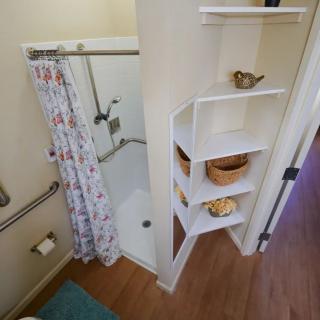 A small bathroom with a shower and decorative shelves.