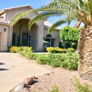 A beautiful residential home with lush landscaping and palm trees.