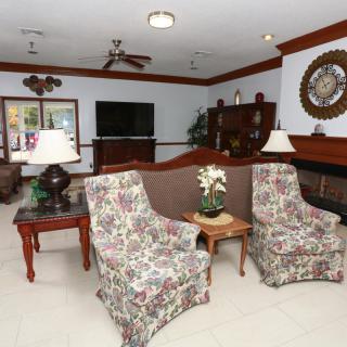 A cozy living room with floral armchairs, a sofa, a television, and a fireplace.