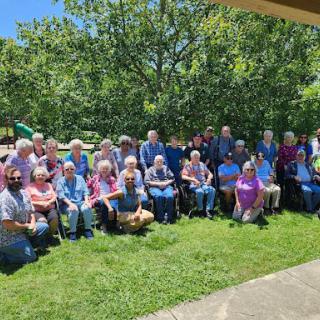 A joyful gathering of seniors enjoying a sunny day in the park.