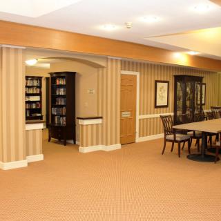 A well-lit library interior with bookshelves and a large reading table.