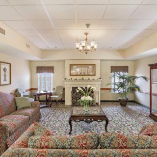 A cozy and elegantly decorated living room with a fireplace, sofas, and a chandelier.