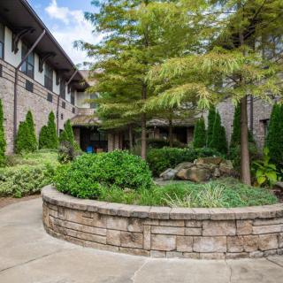 A landscaped courtyard featuring a stone wall and lush greenery surrounded by a brick building.
