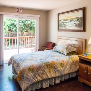 A cozy bedroom with a single bed, bedside table, and a large window opening to a view outside.