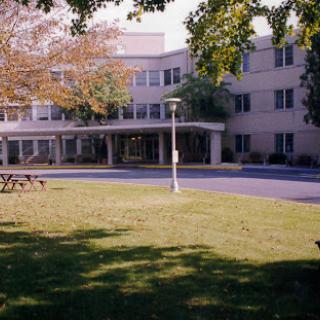 A view of a modern building surrounded by green grass and trees.