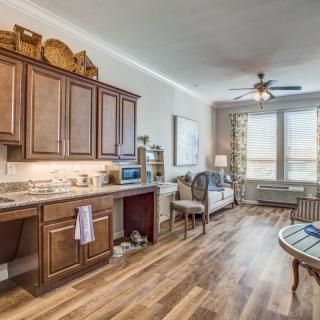A cozy and modern open-plan kitchen and living area with wooden cabinets and hardwood flooring.