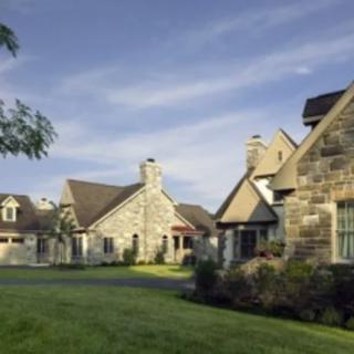 A picturesque stone house with a well-maintained garden under a clear blue sky.