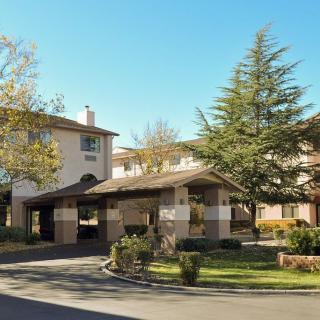 A residential building with a landscaped entrance and driveway on a sunny day.