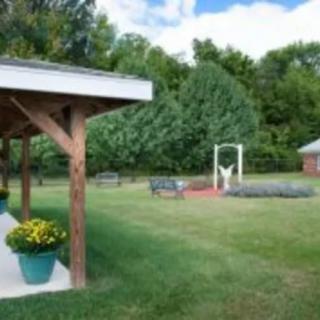 A peaceful outdoor garden area with a patio, trees, and vibrant flowers.