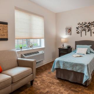 A cozy bedroom with a single bed, armchair, and stylish wall art.