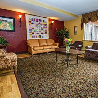 A cozy living room with two sofas, armchairs, a central table, and decorative elements including a painting and indoor plants.