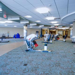 A spacious gym with various exercise equipment and ample lighting.
