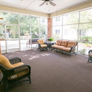 A spacious sunroom with comfortable seating and large glass windows.
