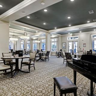 An elegant dining area with neatly arranged tables and chairs, featuring a piano.