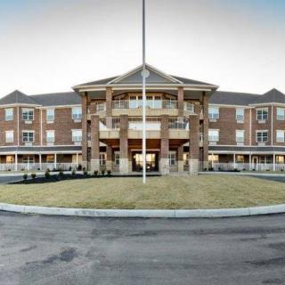 Front view of a large brick building with an entrance overhang and circular driveway.