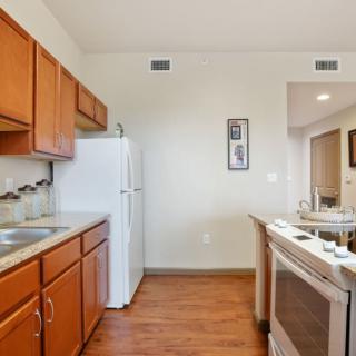 A modern kitchen with wooden cabinets, a white fridge, and a stove.