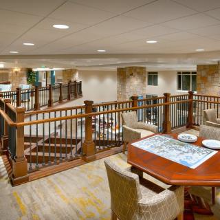 A cozy lounge area with a wooden table and chairs overlooking a staircase.
