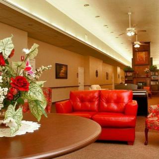 A cozy lobby area with red sofas, a floral arrangement on a table, and bookshelf in the background.